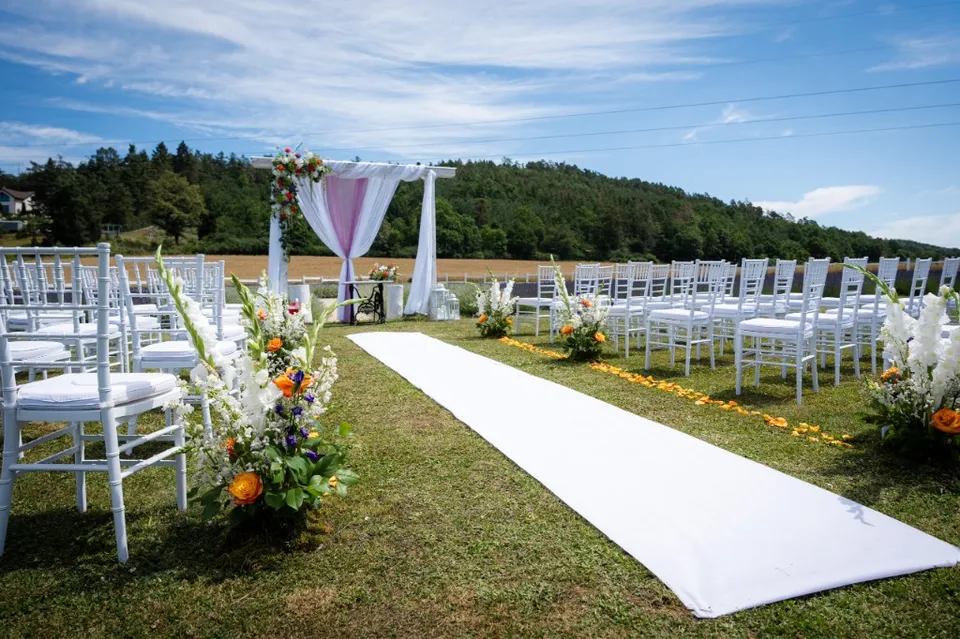 Wide view of the outdoor ceremony — aisle, chairs and floral arrangements