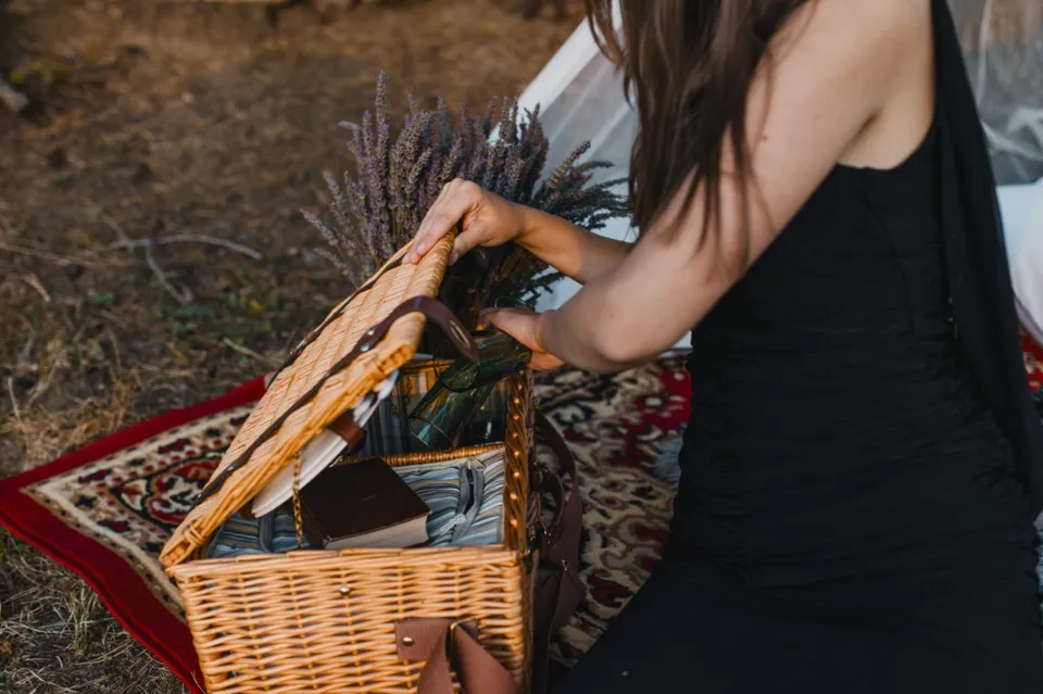Wedding picnic — wicker basket with lavender on a rug, preparing refreshments