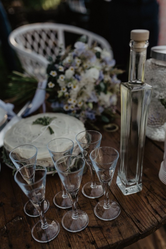 Rustic table with drinks and cake, bouquet in the background