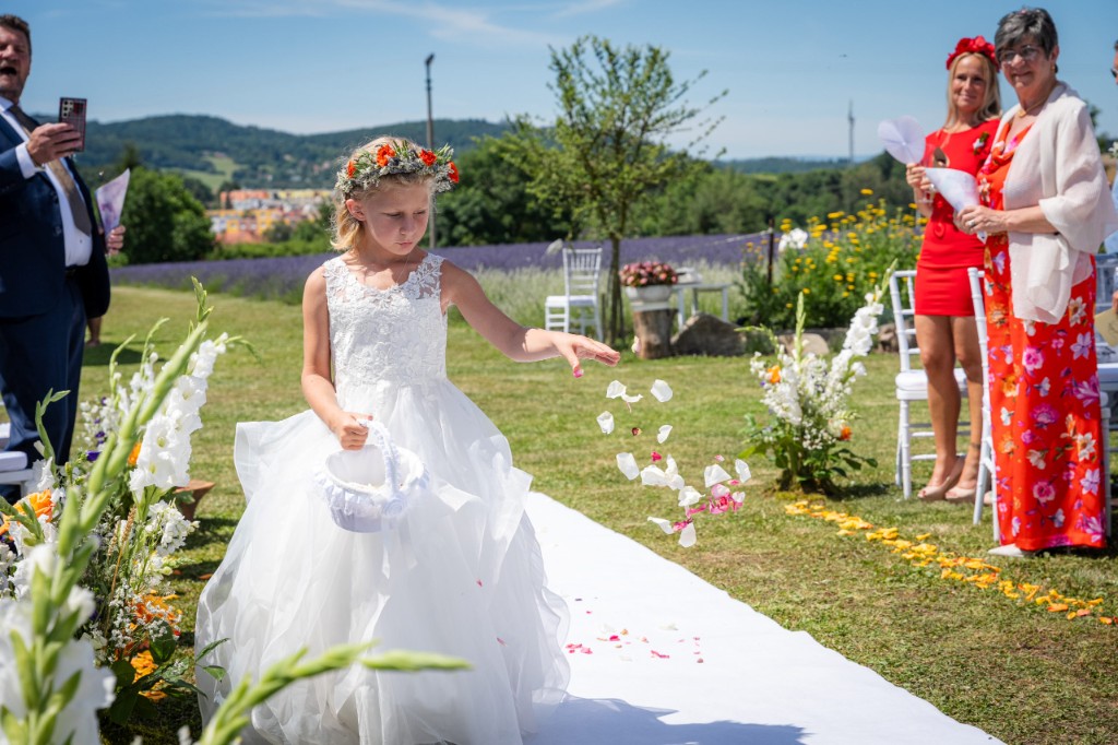 Flower girl scattering petals down the white aisle, lavender field behind