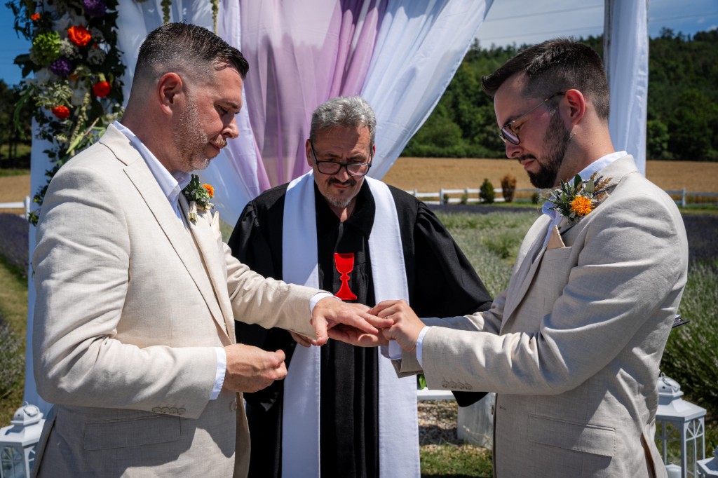 Ring exchange during the ceremony at the draped wedding arch