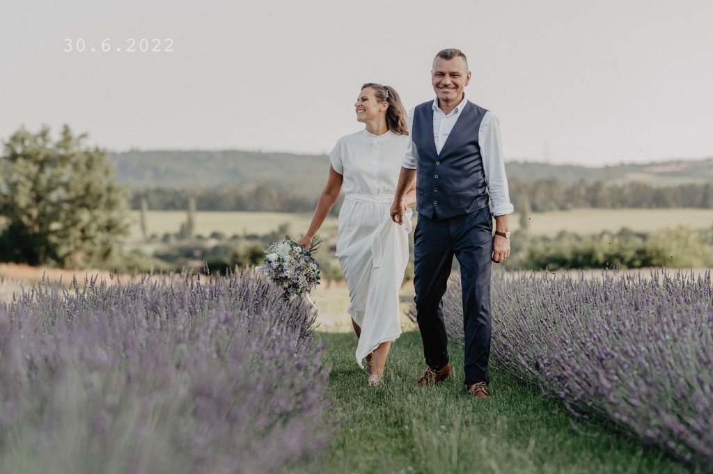 Newlyweds embracing in a sunlit field at sunset