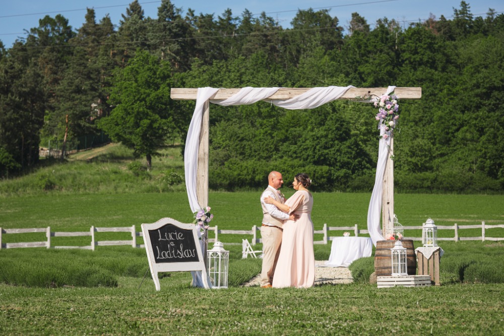 Couple under the rustic wedding arch with floral decoration